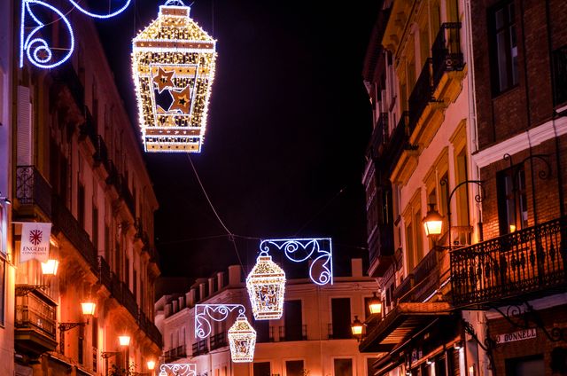 Vibrant street lanterns illuminate a historic street in Seville, creating an enchanting evening atmosphere.